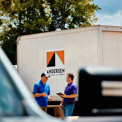 Two men chatting in front of an Andersen Windows truck