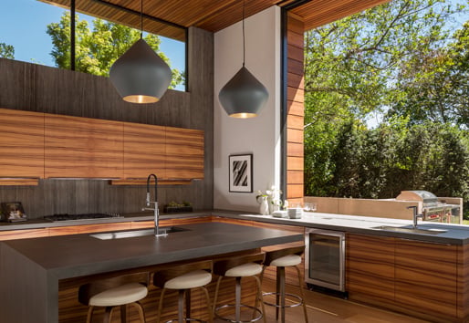 A monumental Andersen® Liftslide Pass-Through Window connects a kitchen with a patio.