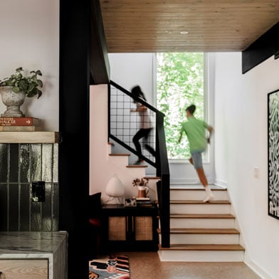 Stairway with kids running up with tall rectangle window letting in natural light